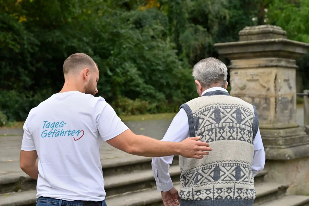Mann hilft älterem Mann bei Spaziergang im Park