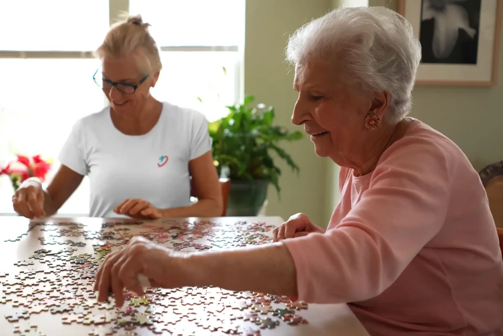 Ältere Dame und Begleitperson beim puzzeln