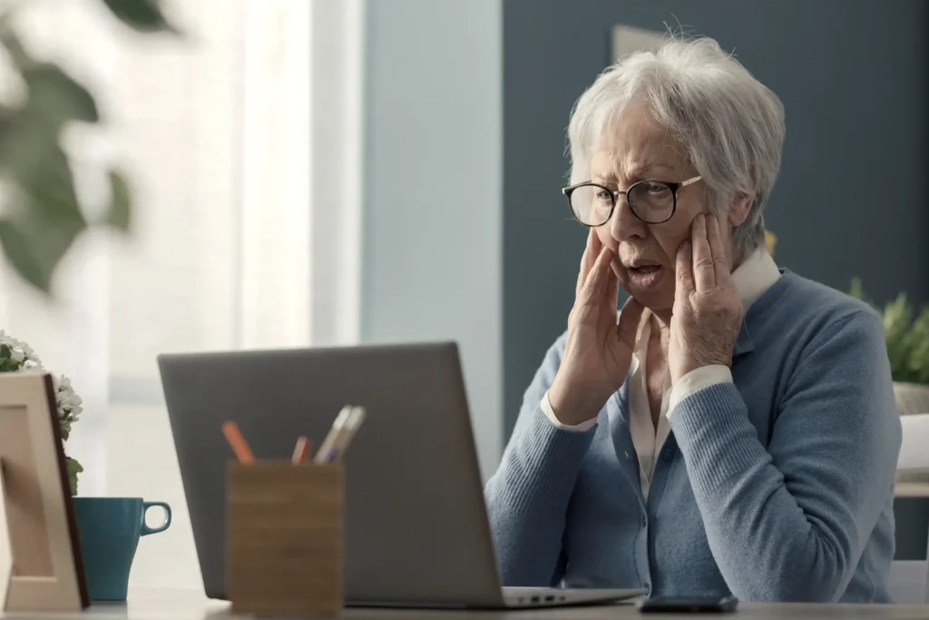 Ältere Dame an Laptop mit besorgtem Gesichtsausdruck