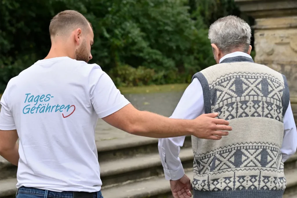 Mann hilft älterem Mann bei Spaziergang im Park